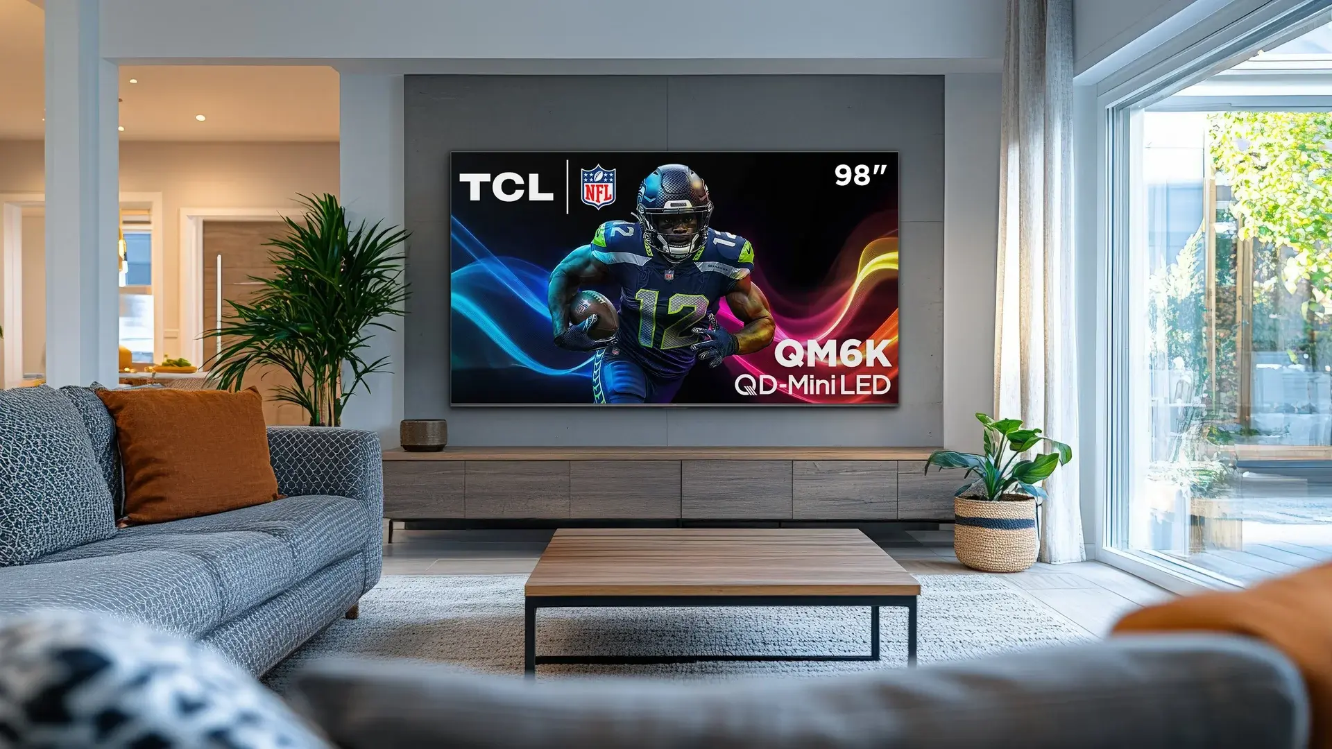 Living room scene featuring TCL TV hanging on wall with football player screensaver