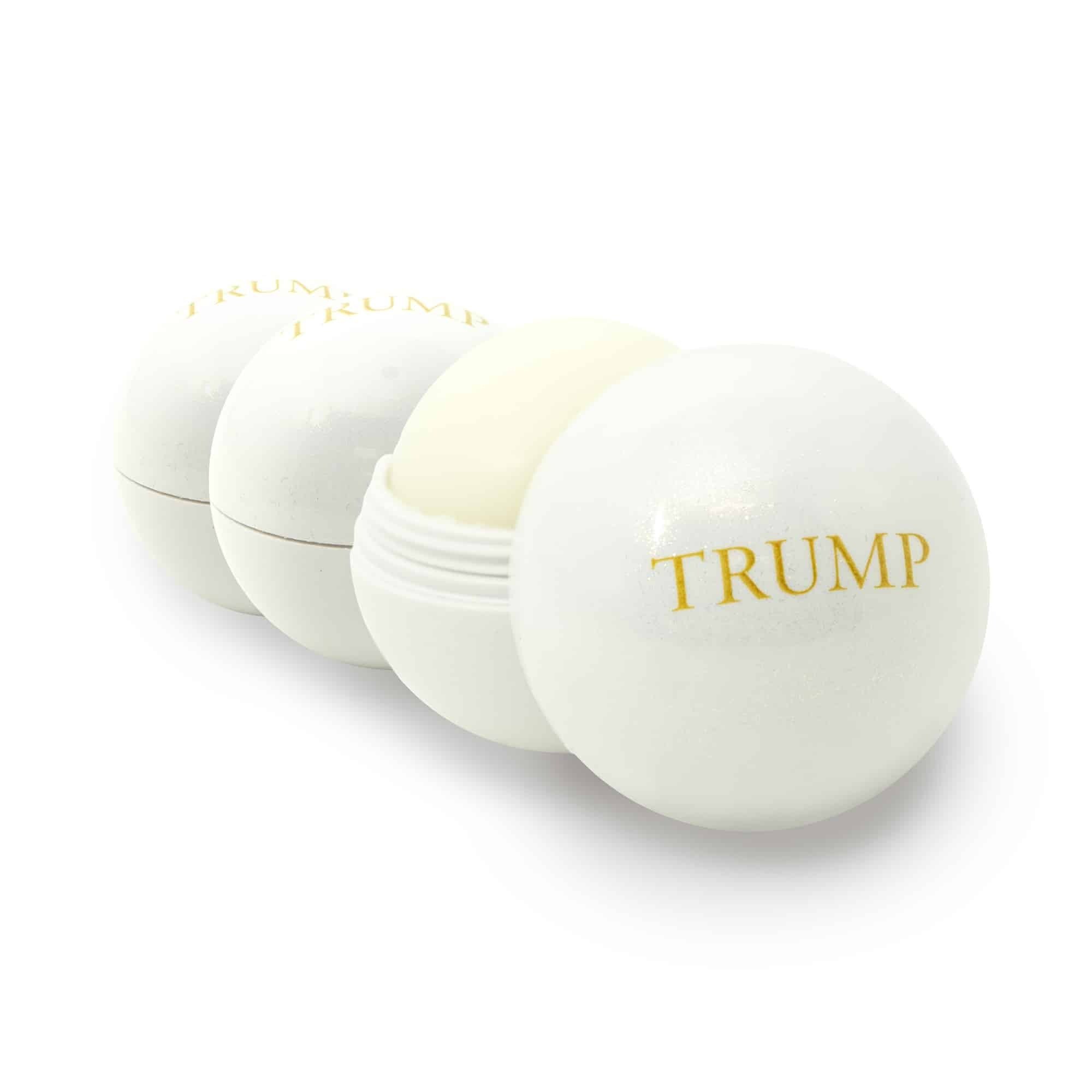 Three white spherical lip balms in a row, each with a gold logo reading "Trump".