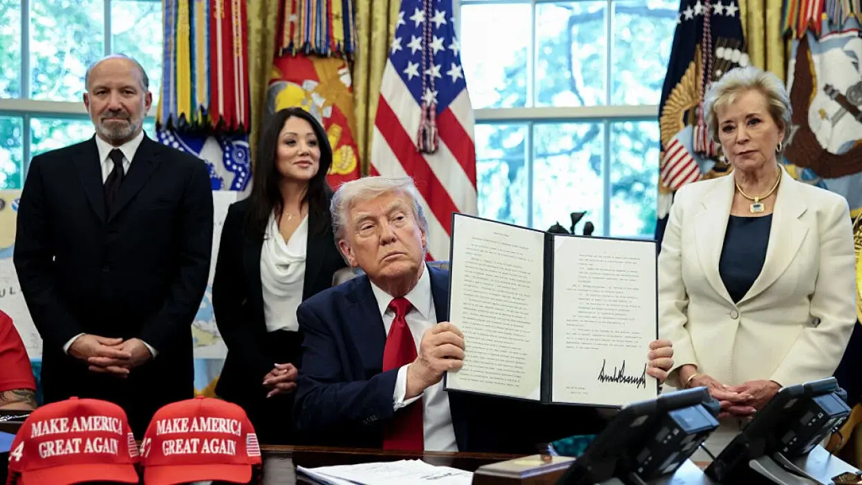 President Donald Trump signs an AI education executive order in the Oval Office with supporters
