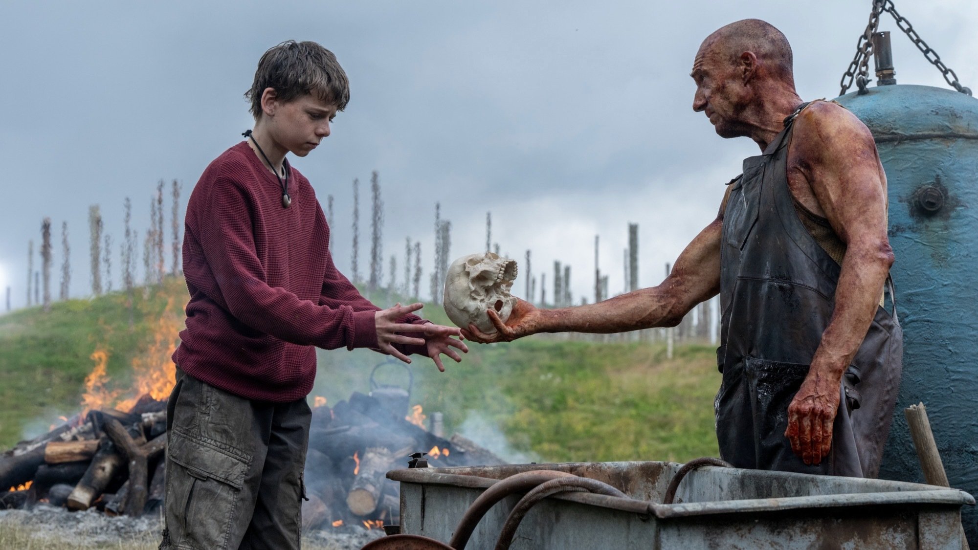 Alfie Williams and Ralph Fiennes hand off a skull in "28 Years Later."