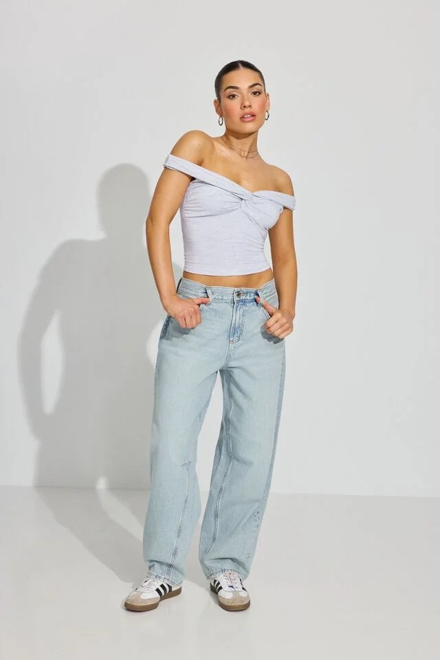 model wearing light wash garage barrel jeans with white top