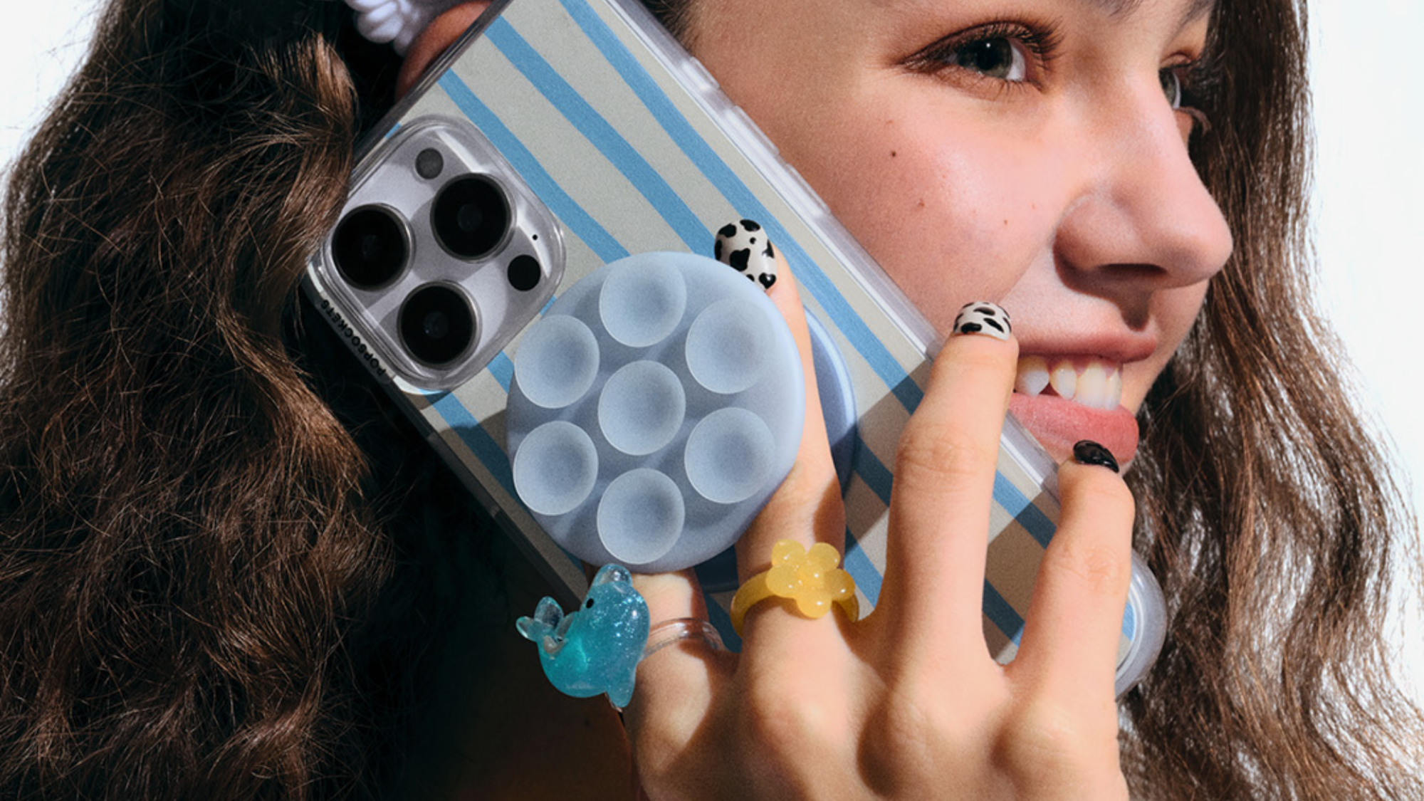 A person holding a phone with a PopSockets Suck-Up Grip attached to it.