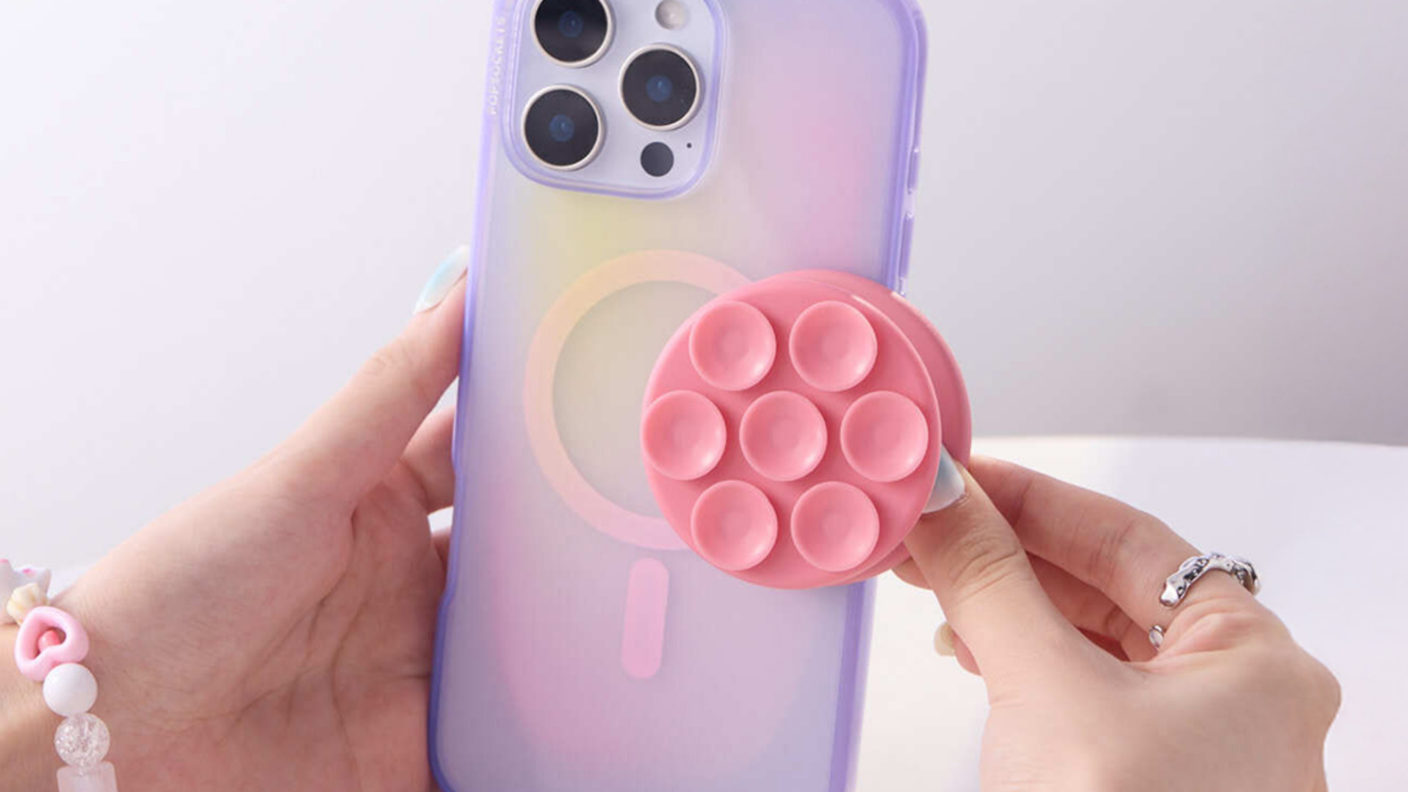 A person placing a Suck-Up Grip on the back of a phone.