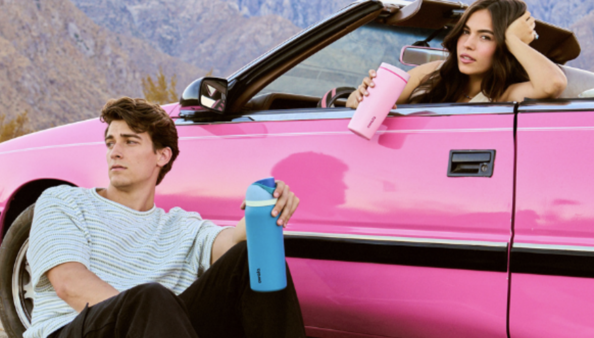 people holding water bottles near pink car