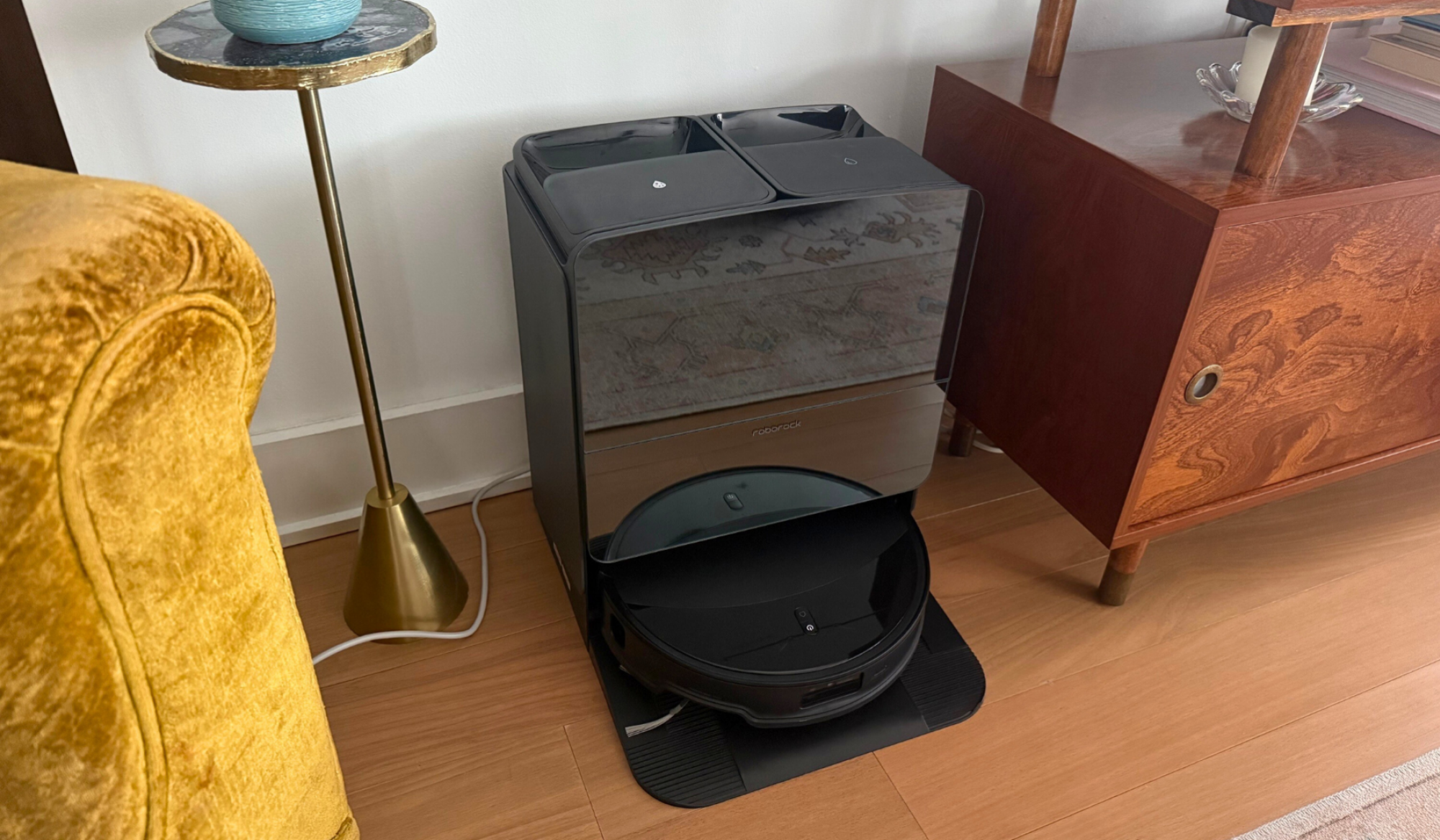Roborock Saros 10R robot vacuum sitting against wall in living room