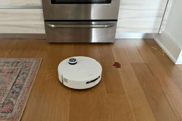 Dreame Aqua10 Ultra Roller robot vacuum cleaning shredded cheese and wine spill on hardwood floor near oven