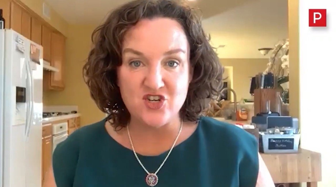 Woman speaking passionately in a kitchen setting, wearing a green top and a necklace, with a focus on her expressive facial gestures.