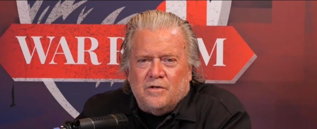 Steve Bannon speaking on his War Room podcast, providing commentary on political issues with a microphone in front of him.